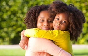 african american mom and daughter hug